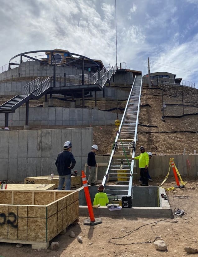 Workers installing Hill Hiker inclined lift track rail at commercial project