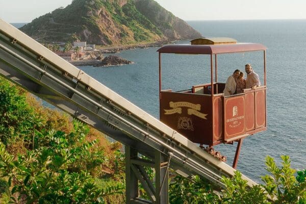 Family rides in commercial inclined funicular tram car with tropical mountain and ocean views in the background from Mazatlan, Mexico