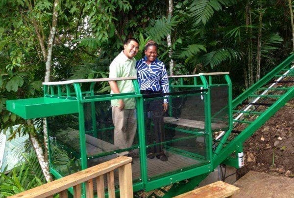 Central American man and woman smile as they ride the hill tram lift at a Eco tourism resort