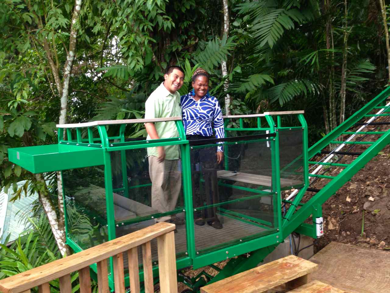 Central American man and woman smile as they ride the hill tram lift at a Eco tourism resort