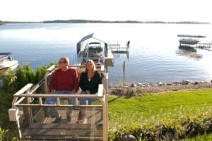 Couple sitting in a residential hillside tram by a sunny lake.