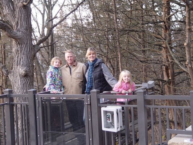 Happy Family On Residential Funicular Waiting For A Lift Down A River Bank