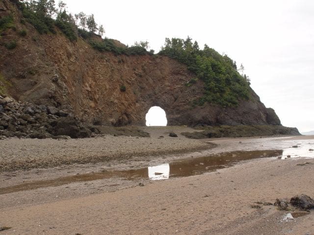 Low tide at Nova Scotia Island project in Canada with natural archway tunnel visible from beach